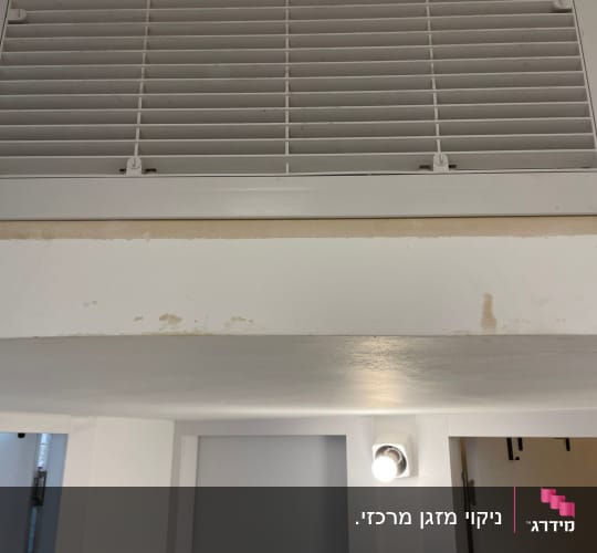 תריס מיזוג אוויר על קיר לבן עם כתמי צבע
